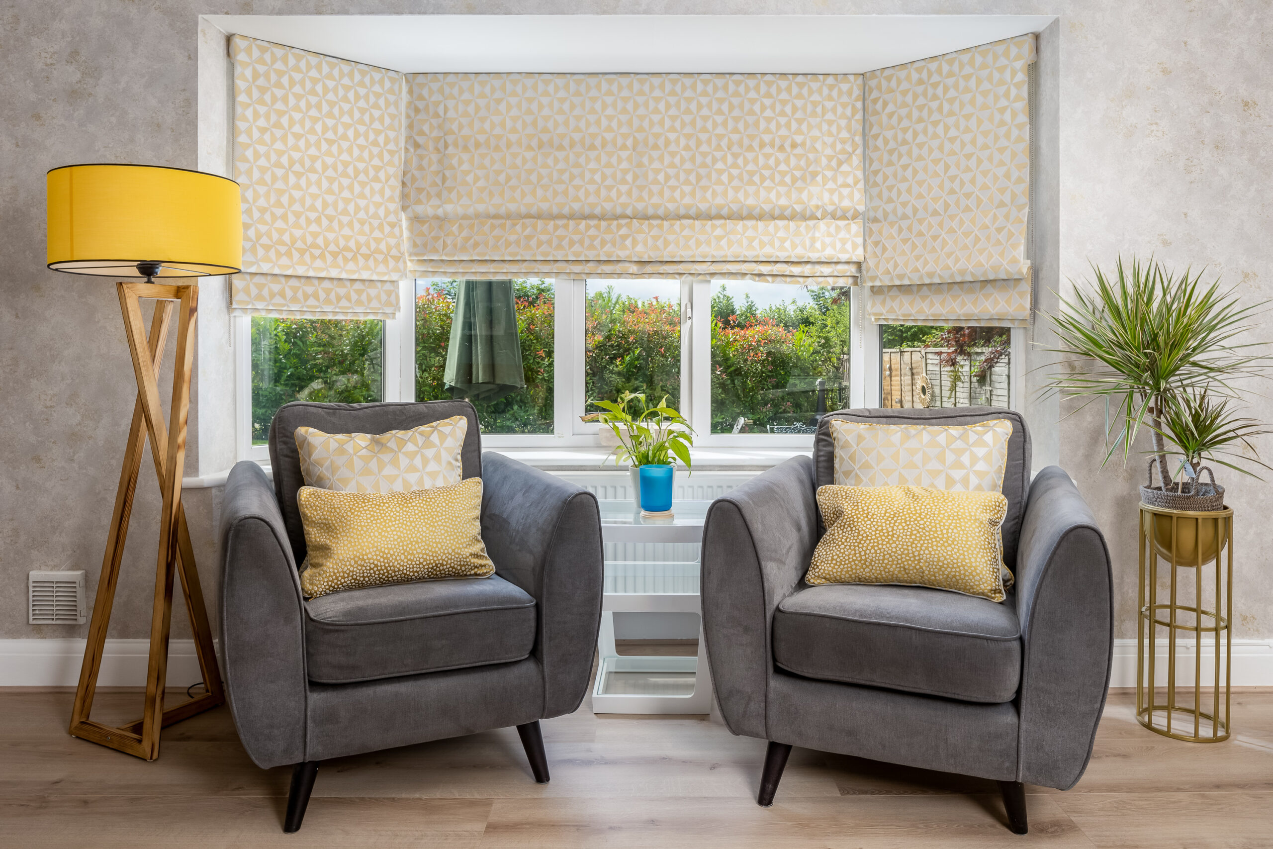 Relaxing seating corner, grey and yellow interiors, window treatment, roman blinds, cushions, floorlamps, cosy corner, window views, natural materials, wood, linen, bamboo